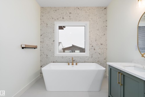 Bathroom featuring a freestanding tub, an accent wall, vanity, and wallpapered walls - Edmonton, AB - Indoor Photo Showing Bathroom