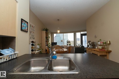 Kitchen featuring dark countertops, open floor plan, and hanging light fixtures - 1004 10136 104 Street, Edmonton, AB - Indoor Photo Showing Kitchen With Double Sink