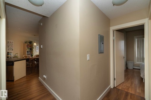Hallway featuring dark wood-type flooring, a textured ceiling, electric panel, and a baseboard heating unit - 1004 10136 104 Street, Edmonton, AB - Indoor Photo Showing Other Room