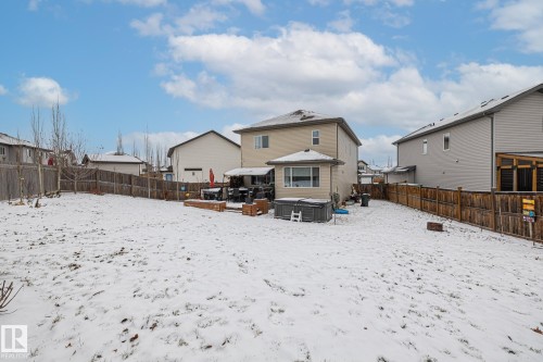 Snow covered house featuring a hot tub, a fenced backyard, and a residential view - 14 Spring Bay, Spruce Grove, AB - Outdoor With Backyard With Exterior