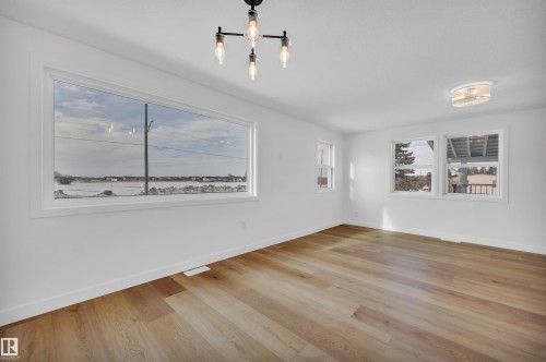 Spare room with light wood finished floors, healthy amount of natural light, and suspended lighting - 5021 46 Avenue, Calmar, AB - Indoor Photo Showing Other Room
