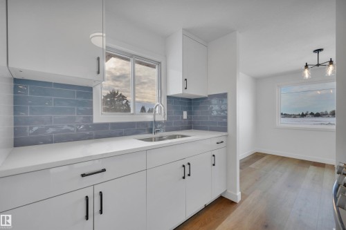 Kitchen with white cabinetry, light wood-type flooring, backsplash, light stone countertops, and pendant lighting - 5021 46 Avenue, Calmar, AB - Indoor Photo Showing Kitchen