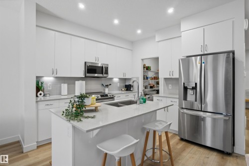 Kitchen featuring stainless steel appliances, light stone countertops, an island with sink, white cabinetry, and recessed lighting - 9882 225A St Nw, Edmonton, AB - Indoor Photo Showing Kitchen With Double Sink With Upgraded Kitchen