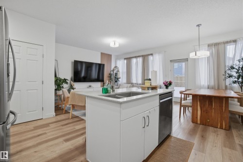 Kitchen featuring white cabinets, open floor plan, stainless steel appliances, a kitchen island with sink, and light wood-style floors - 9882 225A St Nw, Edmonton, AB - Indoor Photo Showing Kitchen With Double Sink