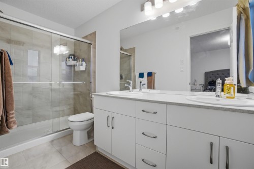 Bathroom featuring double vanity, a shower stall, light tile patterned flooring, and a textured ceiling - 9882 225A St Nw, Edmonton, AB - Indoor Photo Showing Bathroom