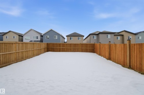 Yard covered in snow with a residential view and a fenced backyard - 9882 225A St Nw, Edmonton, AB - Outdoor With Exterior
