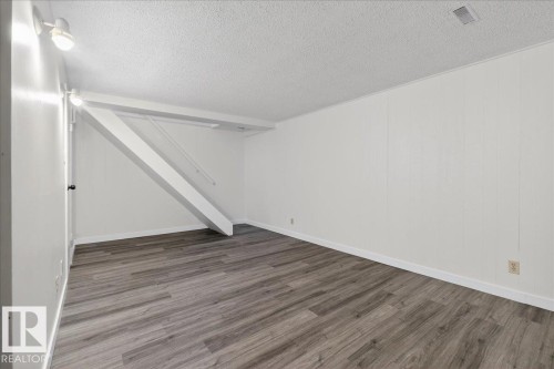 Finished below grade area with a textured ceiling and wood finished floors - 133 Habitat Crescent, Edmonton, AB - Indoor Photo Showing Other Room