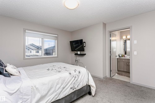Bedroom featuring light carpet, a textured ceiling, and connected bathroom - 2855 16 Avenue, Edmonton, AB - Indoor Photo Showing Bedroom