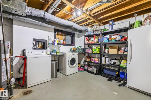 Unfinished below grade area featuring freestanding refrigerator, gas water heater, and separate washer and dryer - 11 Grandview Ridge, St. Albert, AB - Indoor Photo Showing Laundry Room