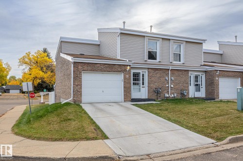 View of front facade featuring brick siding, driveway, a front yard, and an attached garage - 11 Grandview Ridge, St. Albert, AB - Outdoor With Facade