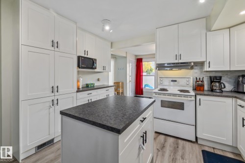 Kitchen featuring white electric range, white cabinets, dark countertops, light wood finished floors, and black microwave - 11 Grandview Ridge, St. Albert, AB - Indoor Photo Showing Kitchen