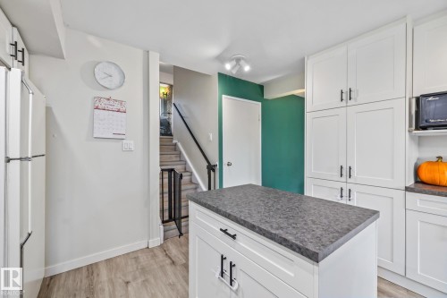 Kitchen with white cabinets, freestanding refrigerator, dark countertops, light wood-style floors, and a kitchen island - 11 Grandview Ridge, St. Albert, AB - Indoor Photo Showing Kitchen