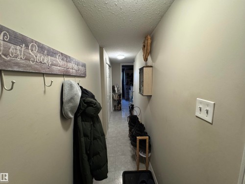 Stairway leading downstairs featuring a textured ceiling - 208 178 Bridgeport Boulevard, Leduc, AB - Indoor Photo Showing Other Room