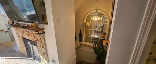 Living room featuring a stone fireplace and hanging lights leading to basement - 208 178 Bridgeport Boulevard, Leduc, AB - Indoor