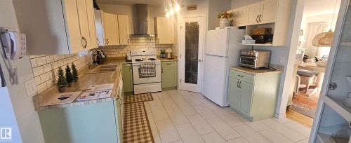 Kitchen with light countertops, white appliances, backsplash, white cabinets, and hanging light fixtures - 208 178 Bridgeport Boulevard, Leduc, AB - Indoor Photo Showing Kitchen With Double Sink