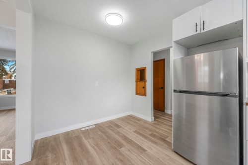 Kitchen with freestanding refrigerator, light wood-style floors, and white cabinetry - 6007 95 Avenue, Edmonton, AB - Indoor