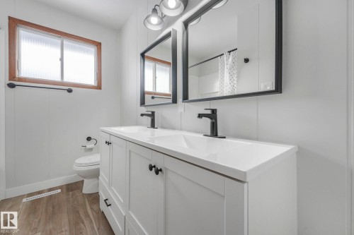 Bathroom with curtained shower, double vanity, and light wood-type flooring - 6007 95 Avenue, Edmonton, AB - Indoor Photo Showing Bathroom