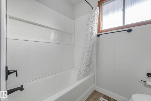 Full bath with shower / bath combo with shower curtain and wood finished floors - 6007 95 Avenue, Edmonton, AB - Indoor Photo Showing Bathroom