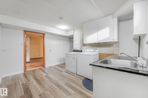 Laundry room with light wood-style floors, washer and dryer, and cabinet space - 6007 95 Avenue, Edmonton, AB - Indoor Photo Showing Laundry Room