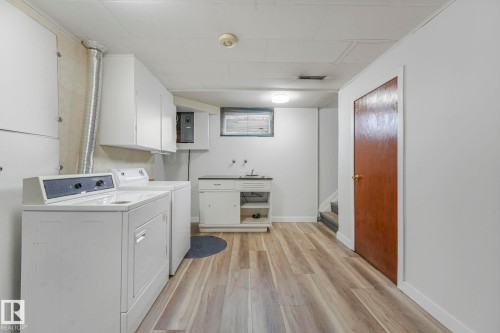 Laundry room with light wood-type flooring, washing machine and dryer, and electric panel - 6007 95 Avenue, Edmonton, AB - Indoor Photo Showing Laundry Room