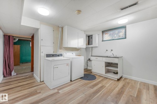 Laundry area featuring light wood-style flooring, washer and dryer, and electric panel - 6007 95 Avenue, Edmonton, AB - Indoor Photo Showing Laundry Room