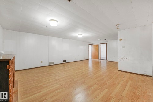 Empty room featuring light wood finished floors and wooden walls - 6007 95 Avenue, Edmonton, AB - Indoor Photo Showing Other Room