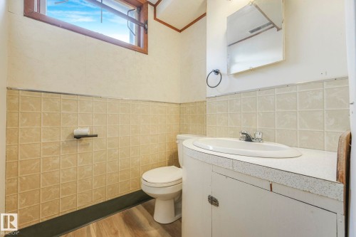 Half bathroom featuring vanity, tile walls, wood finished floors, and wainscoting - 6007 95 Avenue, Edmonton, AB - Indoor Photo Showing Bathroom