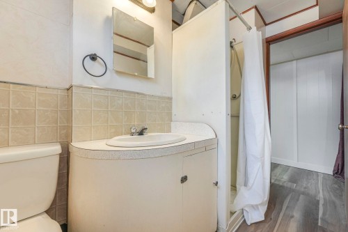 Bathroom with a shower with shower curtain, vanity, dark wood finished floors, and tile walls - 6007 95 Avenue, Edmonton, AB - Indoor Photo Showing Bathroom