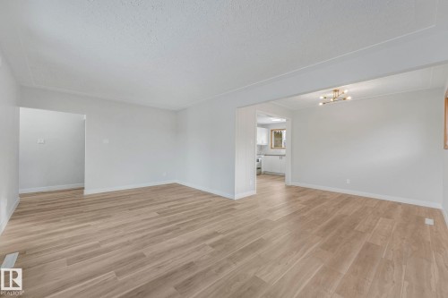 Unfurnished room featuring light wood-style floors, a textured ceiling, and hanging lights - 6007 95 Avenue, Edmonton, AB - Indoor Photo Showing Other Room
