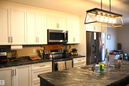 Kitchen with stainless steel appliances, dark stone counters, and white cabinets - 9760 - 107 Street, Westlock, AB - Indoor Photo Showing Kitchen With Double Sink