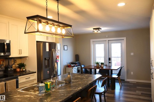 Kitchen featuring white cabinets, stainless steel appliances, dark wood finished floors, pendant lighting, and dark stone countertops - 9760 - 107 Street, Westlock, AB - Indoor Photo Showing Other Room