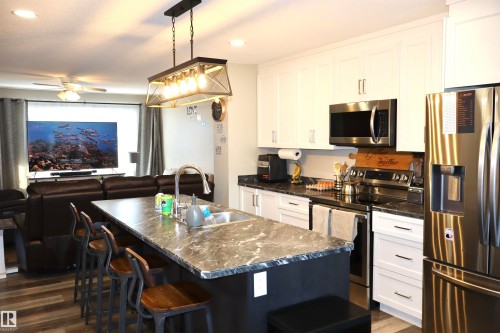 Kitchen featuring stainless steel appliances, open floor plan, white cabinets, and a kitchen bar - 9760 - 107 Street, Westlock, AB - Indoor