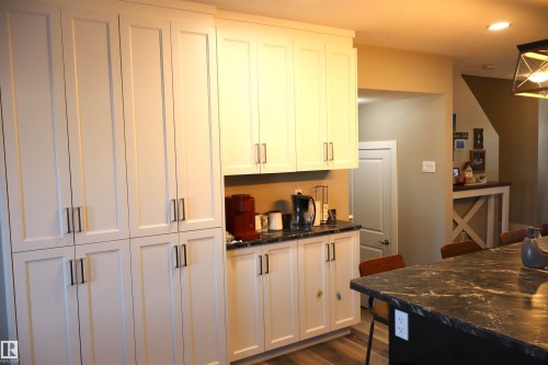 Kitchen featuring dark stone counters, white cabinetry, dark wood-style floors, and recessed lighting - 9760 - 107 Street, Westlock, AB - Indoor