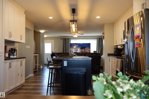 Kitchen with dark countertops, stainless steel appliances, a breakfast bar, pendant lighting, and a center island with sink - 9760 - 107 Street, Westlock, AB - Indoor Photo Showing Other Room