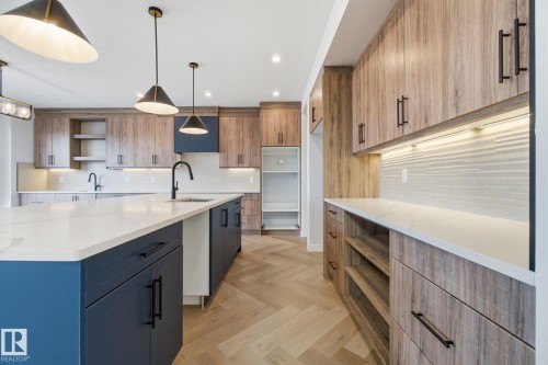 Kitchen featuring open shelves, light stone countertops, parquet floors, a kitchen island with sink, and two tone cabinetry - 17108 2 Street, Edmonton, AB - Indoor Photo Showing Kitchen With Upgraded Kitchen