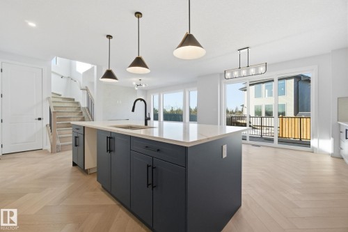 Kitchen with parquet flooring, hanging light fixtures, a center island with sink, light stone countertops, and gray cabinets - 17108 2 Street, Edmonton, AB - Indoor Photo Showing Kitchen With Double Sink With Upgraded Kitchen