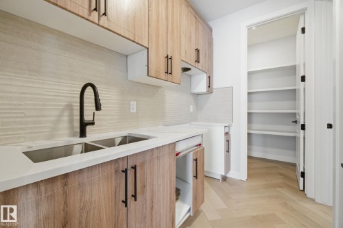 Kitchen with parquet flooring, light wood finish cabinetry, light stone countertops, and backsplash - 17108 2 Street, Edmonton, AB - Indoor Photo Showing Kitchen With Double Sink With Upgraded Kitchen