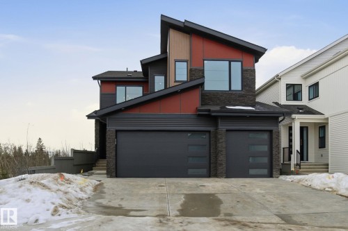 Contemporary home featuring stone siding, driveway, an attached garage, and board and batten siding - 17108 2 Street, Edmonton, AB - Outdoor With Facade