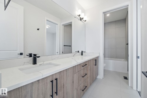 Bathroom featuring double vanity, light tile patterned flooring, and shower / bathtub combination - 17108 2 Street, Edmonton, AB - Indoor Photo Showing Bathroom