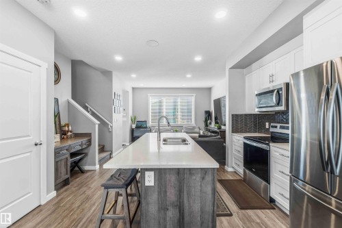 Kitchen featuring stainless steel appliances, a center island with sink, open floor plan, light wood-type flooring, and recessed lighting - 1908 25 Street, Edmonton, AB - Indoor Photo Showing Kitchen With Stainless Steel Kitchen With Double Sink With Upgraded Kitchen