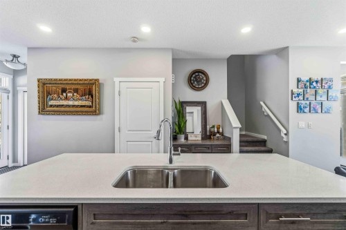 Kitchen featuring recessed lighting, light stone counters, a kitchen island with sink, a textured ceiling, and dishwasher - 1908 25 Street, Edmonton, AB - Indoor Photo Showing Kitchen With Double Sink