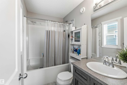 Full bathroom with a textured ceiling, vanity, and shower / bath combo - 1908 25 Street, Edmonton, AB - Indoor Photo Showing Bathroom