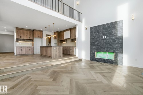 Unfurnished living room featuring a glass covered fireplace, parquet floors, and a high ceiling - 17107 3 Street, Edmonton, AB - Indoor With Fireplace