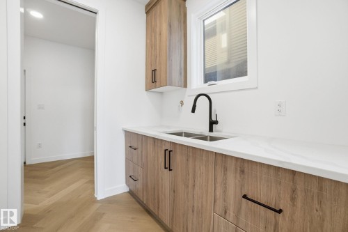 Bar featuring light stone counters, parquet floors, wood finish cabinetry, and modern cabinets - 17107 3 Street, Edmonton, AB - Indoor Photo Showing Kitchen With Double Sink