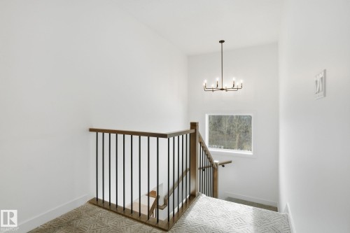 Stairway with hanging lights and carpet flooring - 17107 3 Street, Edmonton, AB - Indoor Photo Showing Other Room