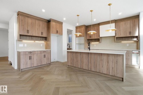 Kitchen featuring open shelves, light stone counters, an island with sink, backsplash, and parquet flooring - 17107 3 Street, Edmonton, AB - Indoor Photo Showing Kitchen