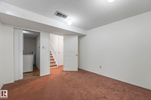Finished below grade area with a textured ceiling, dark colored carpet, and washer / dryer - 19 1415 62 Street, Edmonton, AB - Indoor Photo Showing Other Room