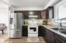 Kitchen featuring white electric range oven, stainless steel fridge, light wood-type flooring, dark wood finish cabinetry, and decorative backsplash - 19 1415 62 Street, Edmonton, AB  - Indoor Photo Showing Kitchen With Double Sink 