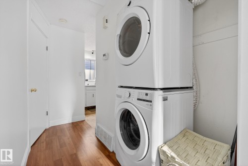 Laundry area featuring wood finished floors and stacked washer and clothes dryer - 10602 66 Avenue, Edmonton, AB - Indoor Photo Showing Laundry Room