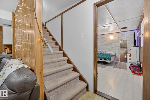 Staircase featuring tile patterned floors and brick wall - 10602 66 Avenue, Edmonton, AB - Indoor Photo Showing Other Room
